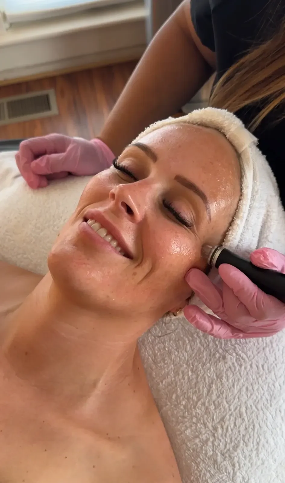 A Rella provider using a facial-treatment handpiece on a patient's cheek