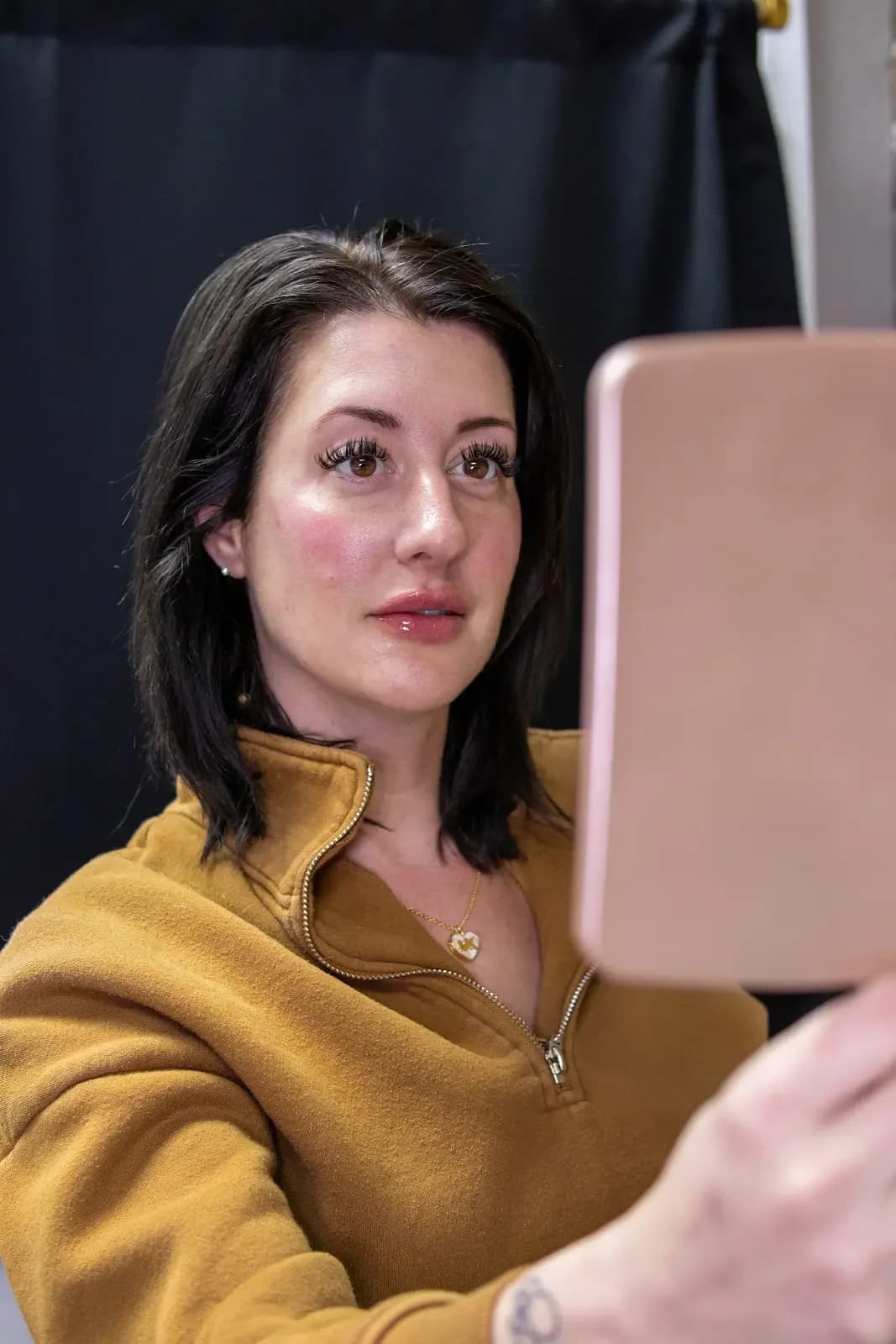 A patient checking her skin in a mirror after treatment