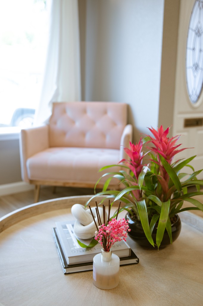 Pink loveseat beside a coffee table with flowers at Rella Vacaville